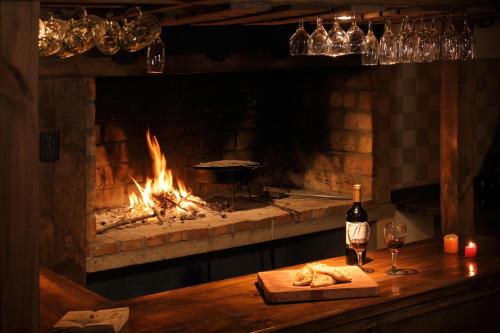 a fireplace with a table with a plate of food and a bottle of wine at La Estancia Cabañas in Villa La Angostura