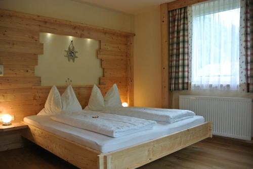 a bedroom with a bed with white sheets and a window at Pension und Apartment Edelweiß in Heiligenblut