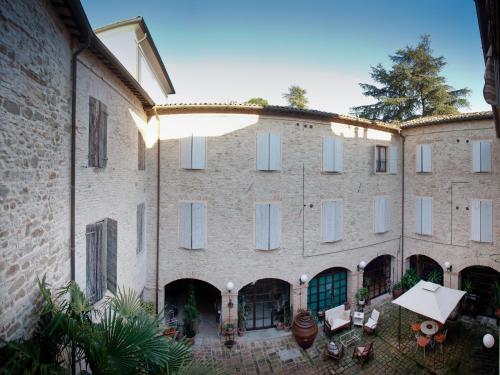 una vista exterior de un gran edificio de ladrillo con mesas y sillas en Relais B&B Corte Dei Turchi, en Longiano