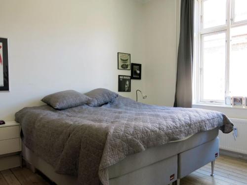 ein Schlafzimmer mit einem Bett mit einer Decke und einem Fenster in der Unterkunft ApartmentInCopenhagen Apartment 1382 in Kopenhagen