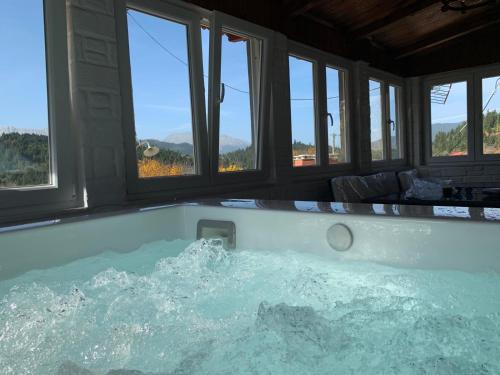 a jacuzzi tub in a room with windows at FOREST VIEW ELISAVET in Pávliani