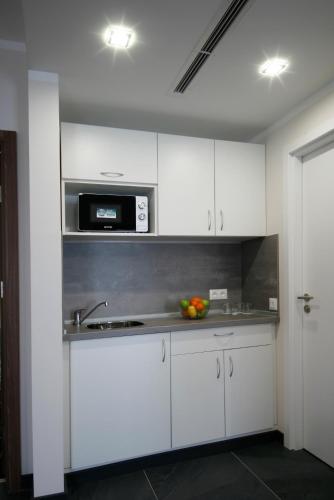 a kitchen with white cabinets and a microwave at Vitosha Park Hotel - Free Indoor Pool & Parking in Sofia