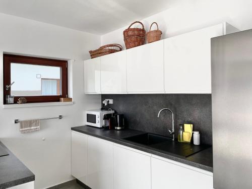 a white kitchen with a sink and a microwave at Free Spirit in Nová Pec