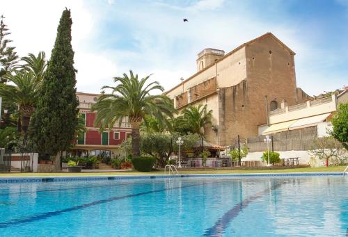 une grande piscine en face d'un bâtiment dans l'établissement Hotel Antiga, à Calafell