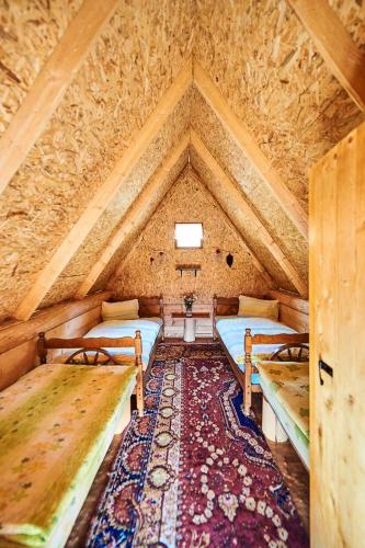 a attic room with two beds and a rug at Sustainable Samel's Cottage Hrid's lake Prokletije in Plav