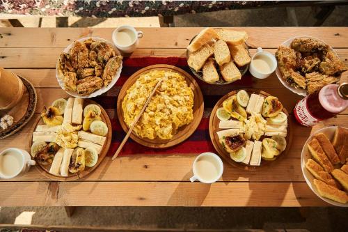 een houten tafel met verschillende soorten broodjes en taarten bij Samel's Cottage Hrid's lake Prokletije in Plav