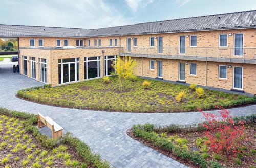 a large brick building with a garden in front of it at PRIMA Inn HOTEL & HOF NEURUPPIN - digitales & rezeptionsloses Motel in Neuruppin