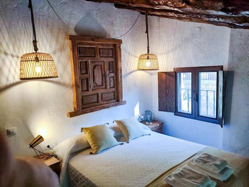 a bedroom with a bed with two lights and two windows at Casa rural El Molino de Bogarra in Bogarra