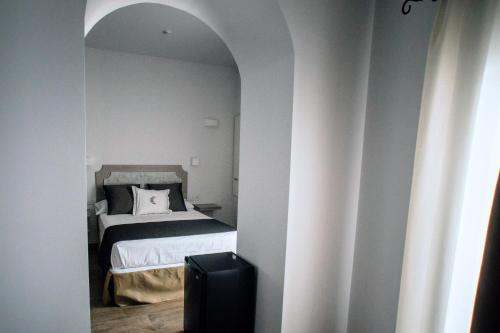 a bedroom with a white bed and a white wall at Patios del Orfebre in Córdoba