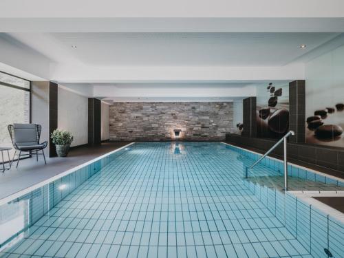 a swimming pool in a building with a brick wall at VAYA Zell am See in Zell am See