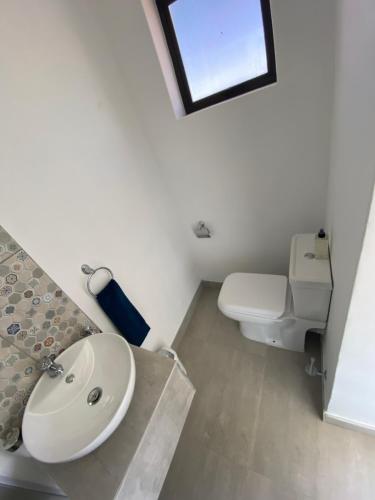 a white bathroom with a sink and a toilet at My-konos in St Francis Bay