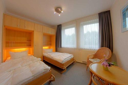 een slaapkamer met 2 bedden, een bureau en een tafel bij KD12 48 Kajediek in Dorum Neufeld
