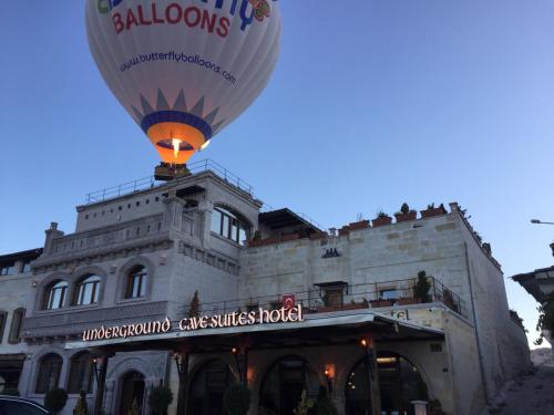 um balão de ar quente a voar em frente a um edifício em Underground Cave Suites Hotel em Goreme