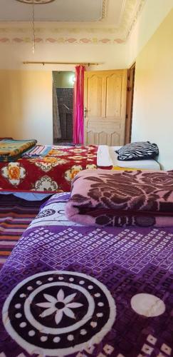 a bedroom with two beds and a purple blanket at Maison D'hote Chez La Famille in Tamellalt
