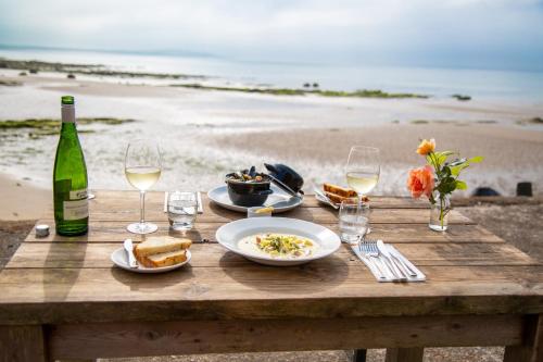 a picnic table with food and wine on the beach at The Crusoe in Leven
