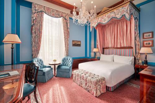 a bedroom with a bed and blue walls and a chandelier at The Lanesborough, Oetker Hotels in London