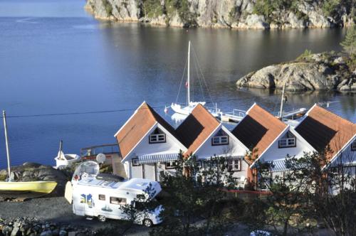 un grupo de casas y un barco en el agua en Aasheim Rorbuer, en Bømlo