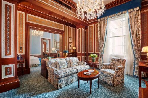 a living room with a couch and chairs and a chandelier at The Lanesborough, Oetker Hotels in London