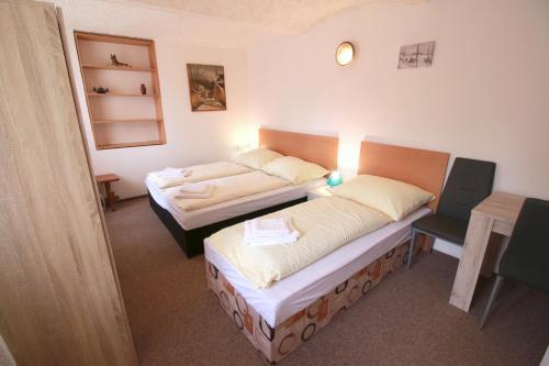 a room with two beds and a table and a desk at Penzion Paseky U Zapadlych vlastencu in Paseky nad Jizerou
