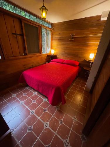 a bedroom with a red bed with two red pillows at Caoni Riverside Suites - Birders Paradise by the river, Ecuadorian Chocó in Puerto Quito