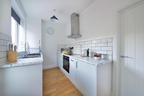 a white kitchen with a sink and a stove at Air Host and Stay - Thomson House - Sleeps 4 2 mins walk from Stockport train station and town centre in Stockport