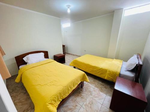 two beds in a room with yellow sheets at Hostal El Gran Gocta in Chachapoyas