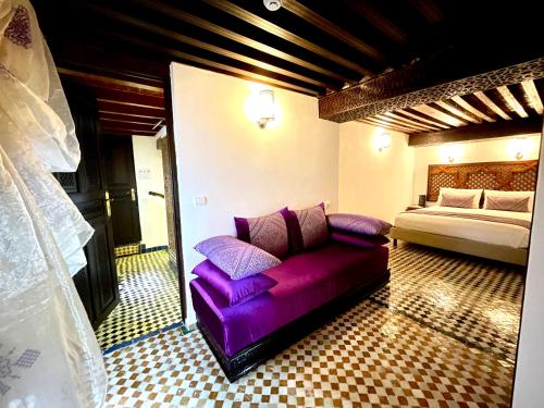 a purple couch in a room with a bed at Le Grand Alcazar - Riad in Fès