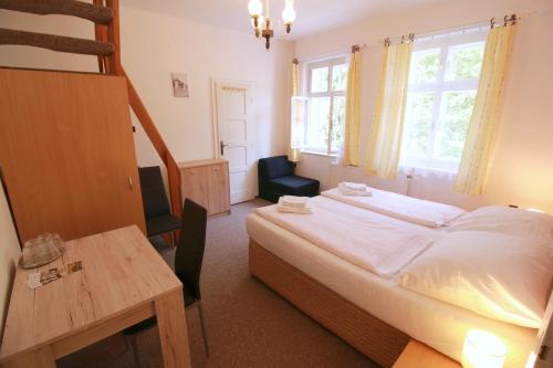 a bedroom with a bed and a table and a chair at Penzion Paseky U Zapadlych vlastencu in Paseky nad Jizerou