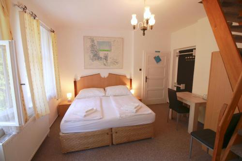 a bedroom with a bed and a desk and a window at Penzion Paseky U Zapadlych vlastencu in Paseky nad Jizerou