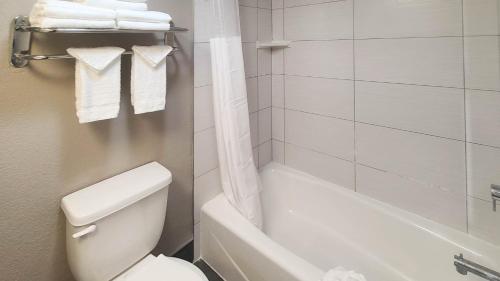 a white bathroom with a toilet and a bath tub at Studio 6 Suites Lawndale, CA South Bay in Lawndale
