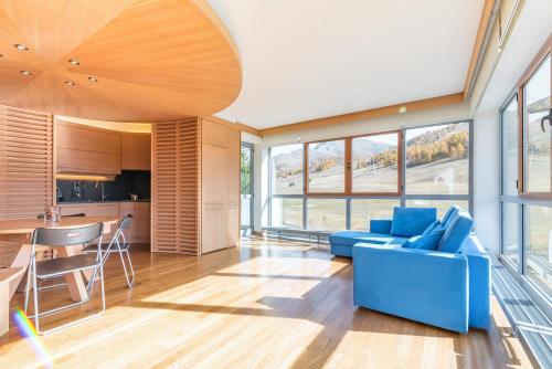 uma sala de estar com um sofá azul e uma cozinha em Terrazza su Sestriere Lux em Sestriere