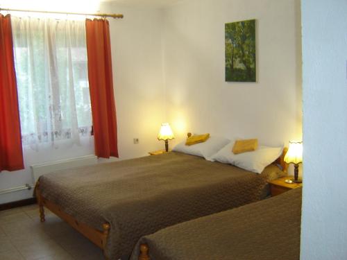 a bedroom with two beds and a window with red curtains at Holiday Home Tanevi in Brezhnitsite