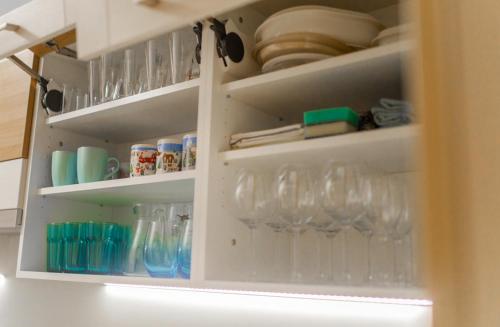 a kitchen cabinet filled with glasses and dishes at Skiapartma - Říčky v Orlických horách in Říčky