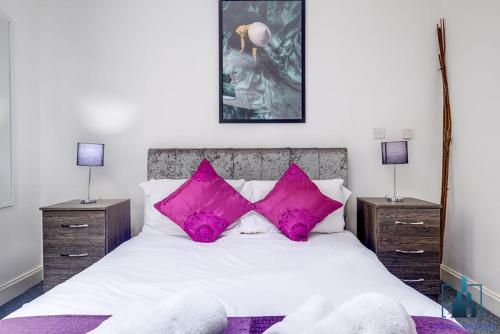 a bedroom with a white bed with pink pillows at City View Apartments Birmingham City Centre in Birmingham