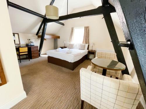 a room with a bed, a chair, and a table in it at The Star and Garter Hotel in Andover
