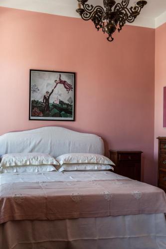 a bedroom with pink walls and a bed with a chandelier at Agriturismo Petrara in Simeri