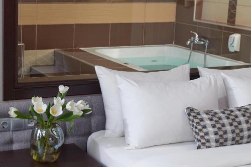 a vase of flowers on a table next to a bath tub at Maison Hotel in Halkidona