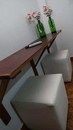 a wooden table with two green bottles with flowers on it at Pousada Regina in Cachoeiro de Itapemirim
