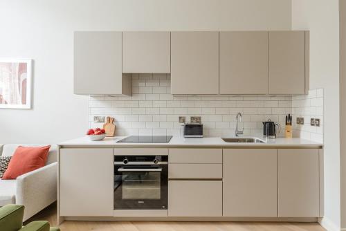 a kitchen with white cabinets and white appliances at Museum Apartments in Edinburgh