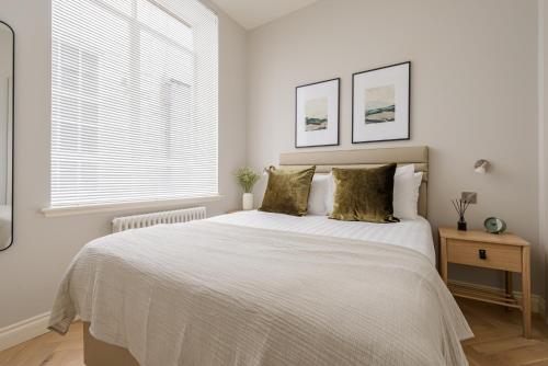 a white bedroom with a large bed and a window at Museum Apartments in Edinburgh