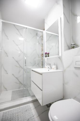 a white bathroom with a shower and a toilet at Apartament CENTRAL in Târgu Ocna