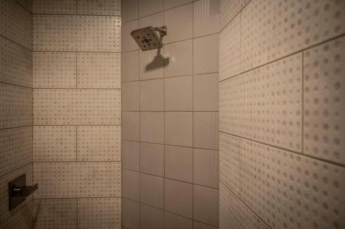 La salle de bains est pourvue d'une douche carrelée de blanc avec un pommeau de douche. dans l'établissement Hotel Broad Ripple, à Indianapolis