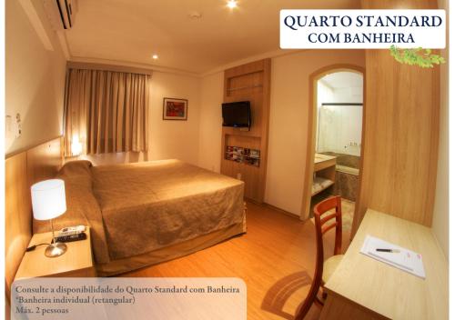 a hotel room with a bed and a table and a mirror at Hotel Ema Palace in São José dos Campos