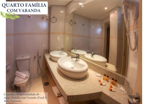 a bathroom with three sinks and a toilet and a mirror at Hotel Ema Palace in São José dos Campos
