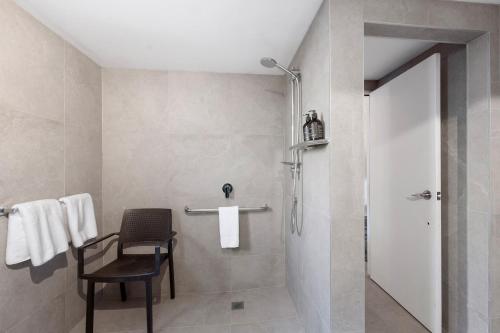 La salle de bains est pourvue d'une douche et d'une chaise. dans l'établissement Lake Lodge Motel Rotorua, à Rotorua