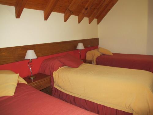 a bedroom with three beds with red and white sheets at Hosteria Maiten Escondido in Villa La Angostura