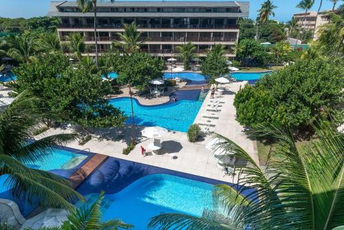 eine Aussicht über den Pool des Resorts mit Palmen in der Unterkunft Nannai Residence Muro Alto Porto Galinhas BeiraMar in Porto De Galinhas