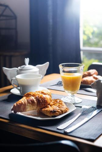 un tavolo con un piatto di prodotti da forno e un bicchiere di succo d'arancia di Edouard & Louise - Chambres d'hôtes a Limoges