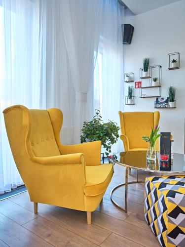 two yellow chairs and a table in a living room at Aparthotel Lumen in Kraków