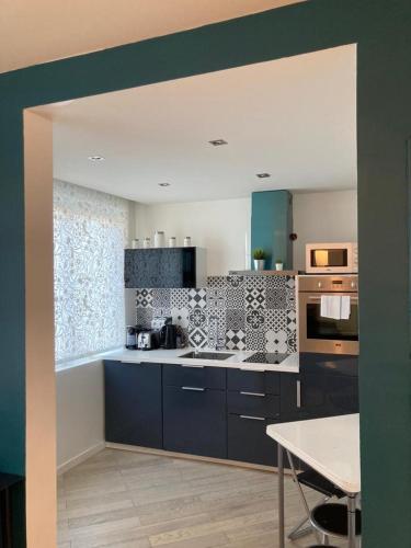 d'une cuisine avec des placards bleus et une table. dans l'établissement Appartement 2P Strasbourg centre - Homme de fer, à Strasbourg